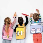niños con mochilas de diferentes colores, escribiendo en lienzo
